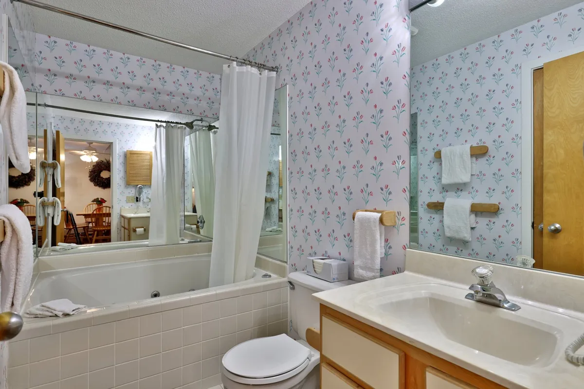 The image features a serene bathroom with a bathtub, mirror, sink, and neatly arranged towels. The calming, spa-like atmosphere invites relaxation and self-care.