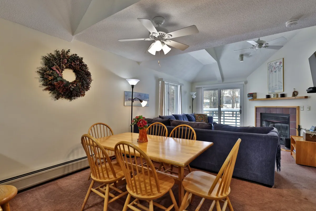 A spacious, cozy interior with a dining table, sofa, and a fireplace adorned with a wreath. The scene is inviting, designed for family gatherings, relaxation, and shared moments, evoking a peaceful, homey atmosphere.